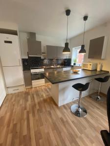 a kitchen with a counter and a island with two bar stools at Grønnegade - tæt på centrum in Esbjerg