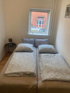 Cama en habitación con 2 almohadas y ventana en Grønnegade - tæt på centrum, en Esbjerg