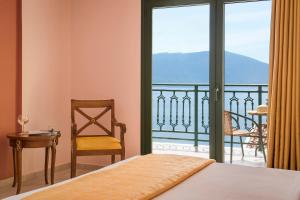 a bedroom with a bed and a chair and a balcony at Kefalonia Bay Palace in Kefallonia
