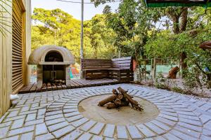 a outdoor patio with a wood fired oven and a bench at Aptos e Studios de frente para a Lagoa da Conceição SDR in Florianópolis