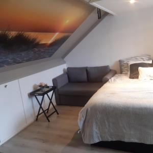 - une chambre avec un lit et un canapé dans l'établissement Studio vlak bij het strand, à Petten
