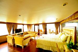 a bedroom with a bed and a couch and a tv at Golden Cruise in Ha Long