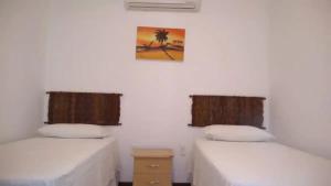 a room with two beds and a picture on the wall at Turtle Bay Village in São Miguel do Gostoso