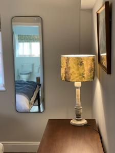 a lamp sitting on a table in front of a mirror at Pear Tree Cabin in Beaulieu