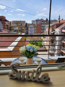 uma mesa com um vaso de flores numa varanda em Apartman Centar em Novi Sad