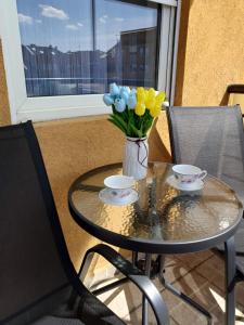 a glass table with two cups and a vase of flowers at Apartman Centar in Novi Sad