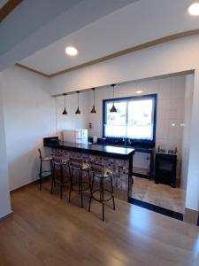 a kitchen with a counter and stools in a room at Casa nova com suítes amplas in Ouro Preto