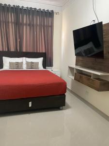 a bedroom with a red bed and a flat screen tv at Hotel Calmelia in Piura
