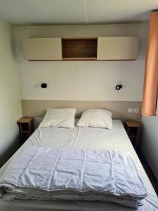 1 cama con sábanas blancas y almohadas en una habitación en Hebergement dans un Domaine à Litteau, en Litteau