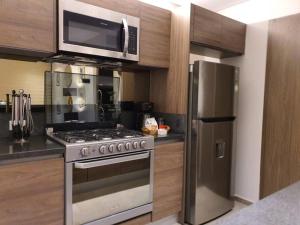 a kitchen with a stainless steel stove and a microwave at Orange & Green Apartment - HP Sur in Mexico City