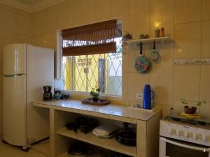 a kitchen with a white refrigerator and a window at Casa à Beira-Mar com Churrasqueira, TV e Wi-fi in Balneário Praia do Leste