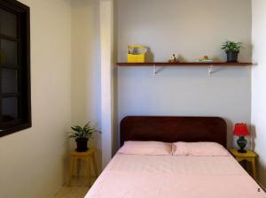 a bed in a bedroom with two plants on the wall at Casa à Beira-Mar com Churrasqueira, TV e Wi-fi in Balneário Praia do Leste
