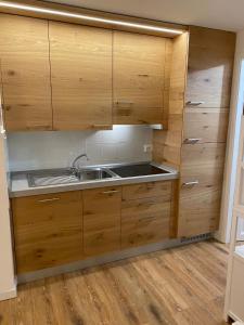 uma cozinha com armários de madeira e um lavatório em La Tana del Gufetto em Mezzana