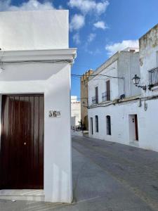 un edificio blanco con una puerta marrón en una calle en Blue Corredera Vejer, en Vejer de la Frontera
