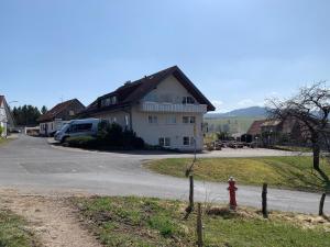 a white house with a red fire hydrant next to a road at Landhaus Schneeberg AusZeit am Küppel & Bright Collection in Gersfeld