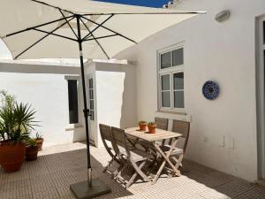 een tafel en stoelen met een parasol op een patio bij Santa Clara Old Town in Albufeira