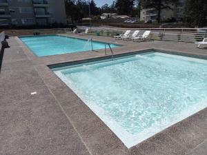 una grande piscina d'acqua con due sedie di Hermoso Dpto entre bosque y piscina. a El Tabo