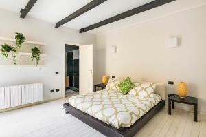 een witte slaapkamer met een groot bed met gele kussens bij Casa la Breva in Lecco