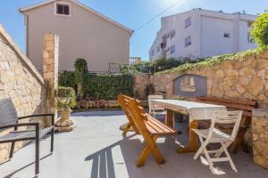 a patio with a table and chairs and a stone wall at Apartments Lemmy in Zadar