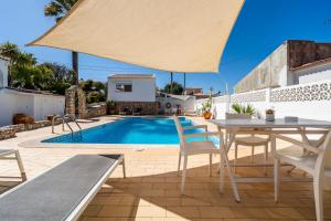 a patio with a table and chairs and a swimming pool at Vivenda Brito in Carvoeiro