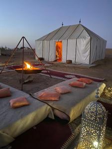 a tent with a bed and a fire in front of it at Dar Marhaba Merzouga in Merzouga