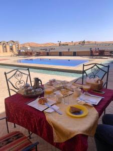 a table with food on it next to a pool at Dar Marhaba Merzouga in Merzouga