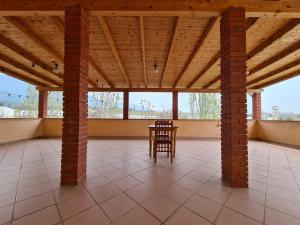 a porch with a table and a wooden ceiling at Bar Kafe Pjetri Guest House in Patza-Kuqani