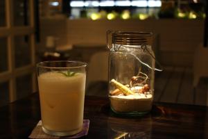 Un vaso de bebida al lado de un tarro de cristal en En- Hostel & Café bar, en Amami