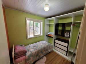 1 dormitorio con paredes verdes, 1 cama y ventana en lugar tranquilo aconchegante perto da natureza, en Nova Petrópolis