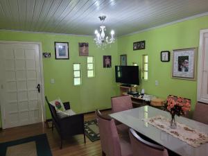 a dining room with green walls and a table and chairs at lugar tranquilo aconchegante perto da natureza in Nova Petrópolis