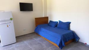 Un dormitorio con una cama con sábanas azules y un refrigerador. en Altos la Villa, en San Rafael