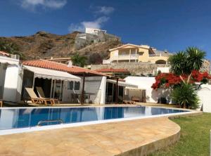 a villa with a swimming pool in front of a house at Bungalow Tauro in Mogán