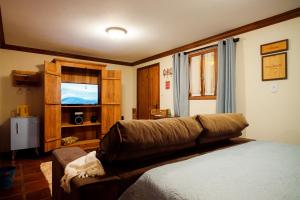 een woonkamer met een bank en een televisie bij Cabana Mimosa in Monte Verde