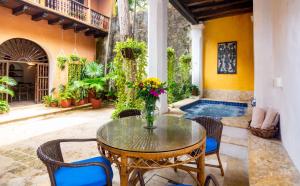 patio ze stołem i krzesłami oraz basenem w obiekcie Casa Baloco By Soho w mieście Cartagena de Indias