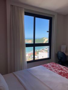a bedroom with a large window with a view of the ocean at Ponta Negra Flats Confort ACCOMMODATIONS AMAQ 18 andar in Natal