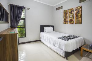 a white bedroom with a bed and a window at Villa Alessa Puncak in Puncak
