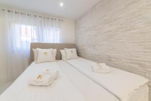 - un lit blanc avec des oreillers blancs et un mur en briques dans l'établissement White House Sarajevo, à Sarajevo