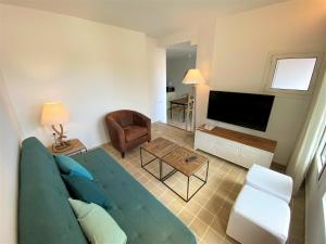 a living room with a blue couch and a television at Hotel Playa Sol in Cadaqués