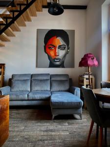 una sala de estar con un sofá azul y una pintura en Apartament Rynek 22 Krosno en Krosno