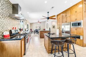 a kitchen with wooden cabinets and a large island with bar stools at Serenity Palm Springs Ranch Permit# 2869 in Palm Springs