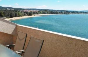 a balcony with chairs and a view of a beach at Impresionantes vistas al mar cerca de Santiago in Boiro