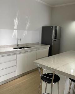 a kitchen with a sink and a refrigerator at Almada Studio 77 in Cunha