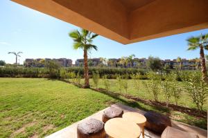 a patio with a table and palm trees in a field at Super Apt T3 Rez de jardin Prestigia Golf Piscine in Marrakesh