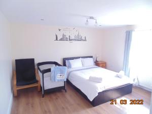 a bedroom with a bed and a chair in it at Two beautiful double bedroom Tulip apartment in Dagenham