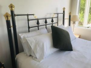 a bed with white pillows and a black head board at Serendipity Adorable Tairua Studio in Tairua
