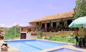 a villa with a swimming pool in front of a house at Santa Monica Barichara in Barichara
