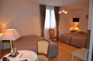 a hotel room with two beds and a table at Hostellerie le Clos du Cher in Noyers-sur-Cher