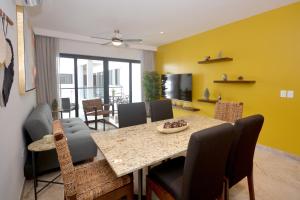 comedor con paredes amarillas, mesa y sillas en IPANA Luxury Apartments by Vacaciones.Yeah en Playa del Carmen