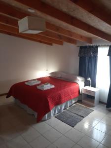 - une chambre avec un lit rouge et une couverture rouge dans l'établissement Hospedaje Naim, à Ushuaia