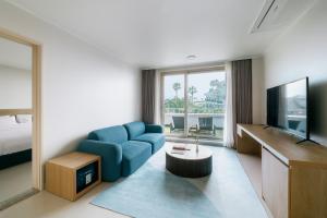 a living room with a blue chair and a television at Bloom Hotel in Seogwipo